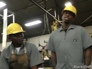 Cute blonde office chick with a bunch of black workers in the factory